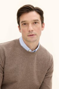 Ruskea neulepusero, jossa on pyöreä pääntie, on kerroksittain vaaleansinisen kauluspaidan päällä. Suora pinta ja neutraalit värit tekevät siitä sopivan epämuodolliseen käyttöön.