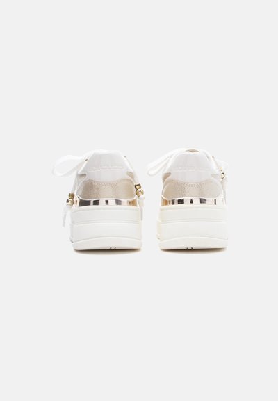 Λευκά παπούτσια πλατφόρμας με χρυσές λεπτομέρειες, κορδόνια δεμένα σε φιόγκους, από οπίσθια όψη σε λευκό απλό φόντο.