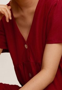 Abito in cotone rosso con scollo a V profondo, maniche corte e vita arricciata, dotato di leggeri bottoni e una texture liscia.
