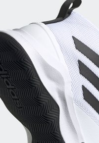 Semelle et dessus de basket Adidas blanc et noir avec trois bandes noires et motif texturé antidérapant sur la semelle extérieure noire.