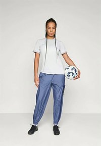 Athletic outfit featuring a light grey short-sleeve shirt and blue track pants with elastic cuffs, paired with a patterned soccer ball.