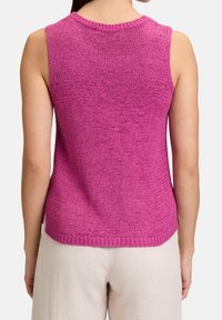 Haut en tricot sans manches de couleur fuchsia, avec un col rond côtelé, un tissu texturé et un ourlet droit. Coupe décontractée avec un design simple.