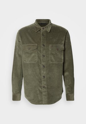 Olivgrünes Cordhemd mit Knopfleiste, zwei Brusttaschen und Kragen. Verfügt über braune Knöpfe und ein geripptes Muster.