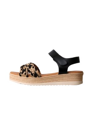 Sandale compensée avec bride avant tressée beige et noire, bride de cheville noire avec velcro, et semelle plate-forme tissée beige.