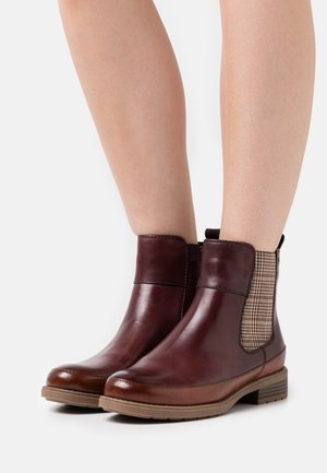 Bottines en cuir marron avec des panneaux élastiques sur les côtés, des accents de plaid texturé, des semelles en caoutchouc marron et une pointe arrondie.