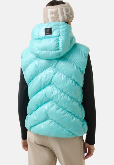 Hellblaues Pufferwest mit einem Zickzackmuster, ausgestattet mit Kapuze und schwarzem Etikett. Die Weste hat eine glänzende Textur und ist über einem Langarmoberteil getragen.