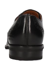 Zapato de cuero negro con detalles de brogue, textura suave y tacón redondeado. Logo estampado en el lateral. Diseño clásico con acabado pulido.