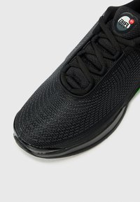 Black athletic shoe with textured mesh upper, lace closure, air cushioning in sole, and contrasting colored accents on heel.