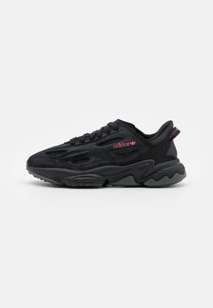 Czarny sneaker Adidas z teksturowaną podeszwą, siateczkową i zamszową cholewką, wiązany, z różowym logo Adidas po boku i na pasku przy pięcie.
