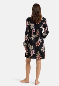 Floral wrap dress in black fabric featuring large pink and beige flowers, long sleeves, elastic waist, and mid-thigh length.