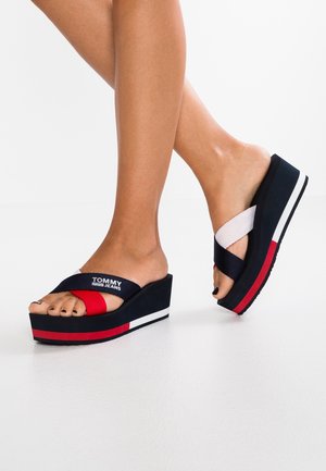 Sandały na platformie w granatowo-czerwono-białej kolorystyce. Tkaninowe paski krzyżujące się na stopie. Posiadają grubą podeszwę na wedges, dodającą wysokości.