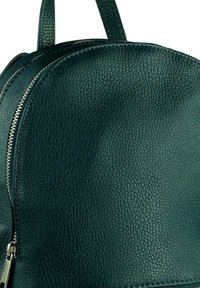 Turquoise leren rugzak met een gestructureerd oppervlak, rond model en zilveren ritsdetails. Voorzien van een handvat aan de bovenkant voor comfortabel dragen.