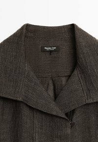 Veste tissée gris foncé avec un large col, fermeture à boutons et tissu texturé. L'étiquette indique "Massimo Dutti, Fabriqué au Portugal."