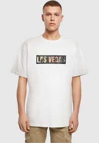 Hvid bomulds T-shirt med et stort grafisk print med "LAS VEGAS" i et rektangulært design, blandede farver og detaljer fra byen.