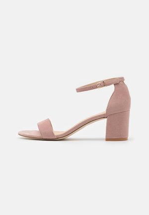 Single dusty pink suede sandal with block heel, ankle strap, and open toe, shown in side profile on white background.