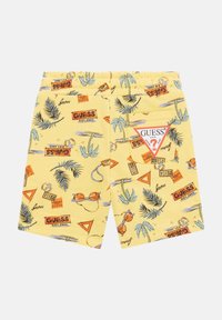 Pantalones cortos amarillos con un diseño tropical que incluye palmeras, gafas de sol y logotipos. Cintura elástica y una etiqueta triangular en el bolsillo trasero.