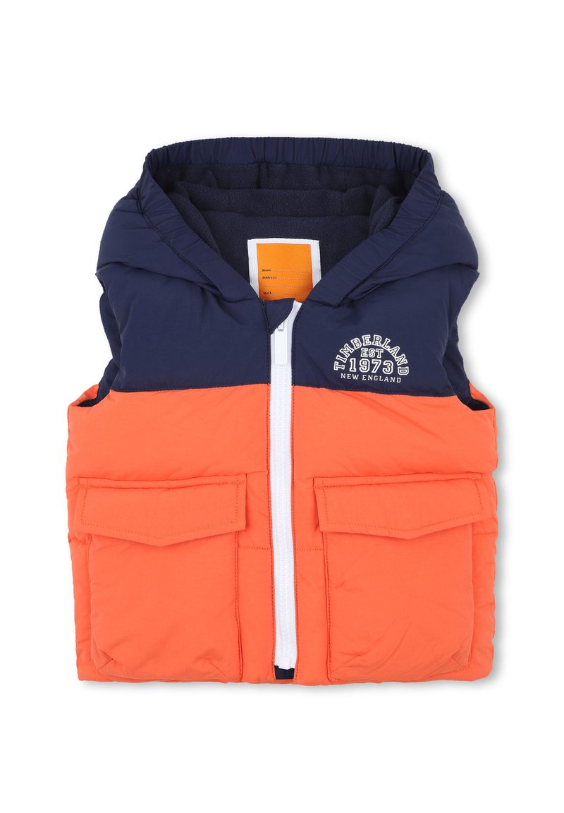 Gilet a blocchi di colore con parte superiore blu navy e parte inferiore arancione brillante. Presenta una chiusura con zip, due tasche frontali e un cappuccio. Materiale morbido e imbottito.