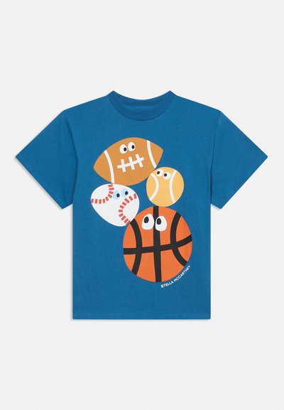 T-shirt bleu à manches courtes avec des dessins style cartoon de football, baseball, tennis et basketball, chacun avec des yeux sur le devant.