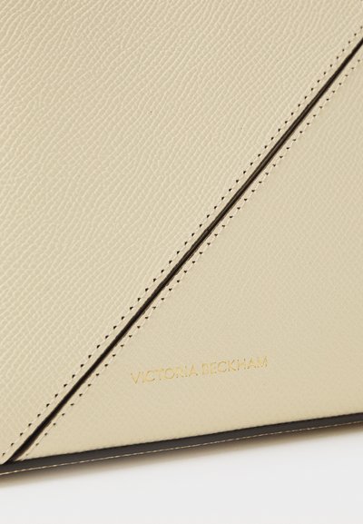 Geantă din piele bej, cu o suprafață texturată, detalii cu cusături diagonale și logo-ul aurit „Victoria Beckham” embosat în partea de jos.