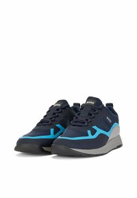 Baskets de sport bleu marine avec des accents turquoise contrastants, dotées d'une tige en tissu lisse, d'une semelle texturée et d'un design à lacets.