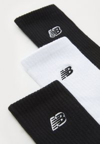 Three pairs of ribbed socks in black and white, featuring embroidered logo accents in contrasting colors at the top.