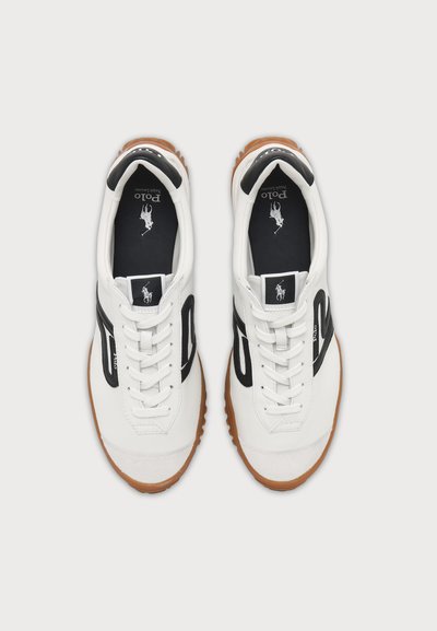 Ζεύγος λευκά δερμάτινα sneakers Polo Ralph Lauren με μαύρες πλευρικές ρίγες, λευκά κορδόνια, καφέ λαστιχένιες σόλες και λογότυπο στις εσωτερικές σόλες και στις ετικέτες της γλώσσας.