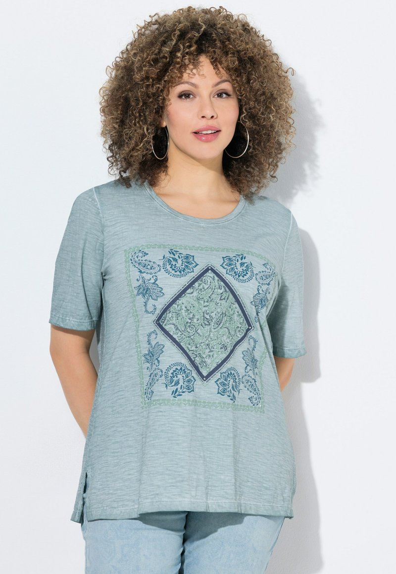 Camiseta de manga corta azul claro con un acabado texturizado, que presenta un estampado central en forma de diamante con motivo paisley en tonos verdes y azul marino.