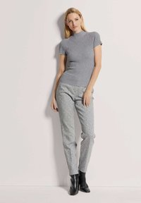 Grijze geribbelde top met korte mouwen, gecombineerd met lichtgrijze gestreepte broek en zwarte puntige enkellaarsjes. Glad textuur en aansluitend ontwerp.