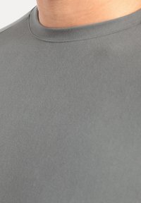 Grijze kortemouwenshirt van een gladde stof met een ronde halslijn en subtiele textuur, zonder zichtbare naden of patronen.