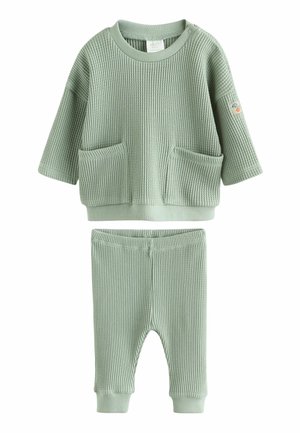 Miękki, teksturowany, szałwiowy zielony dwuczęściowy strój dla dziecka z długim rękawem, posiadający dwie przednie kieszenie oraz dopasowane spodnie z mankietami przy kostkach.