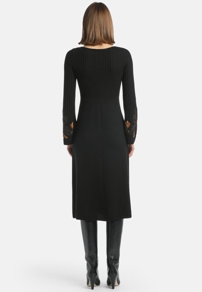 Fekete, hosszú ujjú pulóverruha bordázott testtel, sima szoknyával és arany hímzéssel az ujjak végén. Térdig érő fazon.