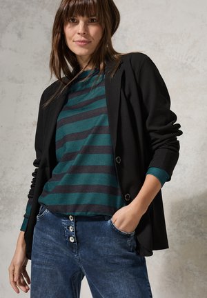 Musta bleiseri teal ja musta raidallinen paita päällä, yhdistettynä denimpantsuihin, joissa on valkoiset napit. Sujuva kangas, rento malli ja epämuodollinen suunnittelu.