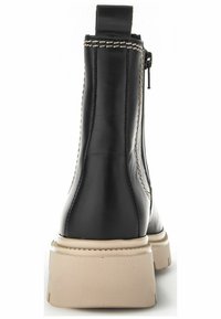 Botín negro de cuero con suela beige, que presenta un zipper lateral, detalles de costura y una lengüeta en la parte trasera para facilitar su uso.
