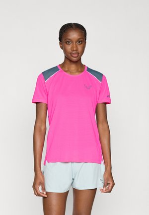 Vaaleanpunainen urheilupaita, jossa on harmaat olkatoppaukset, lyhyet hihat ja pyöreä pääntie. Kevyt materiaali, sileä rakenne ja sivuhalkiot.