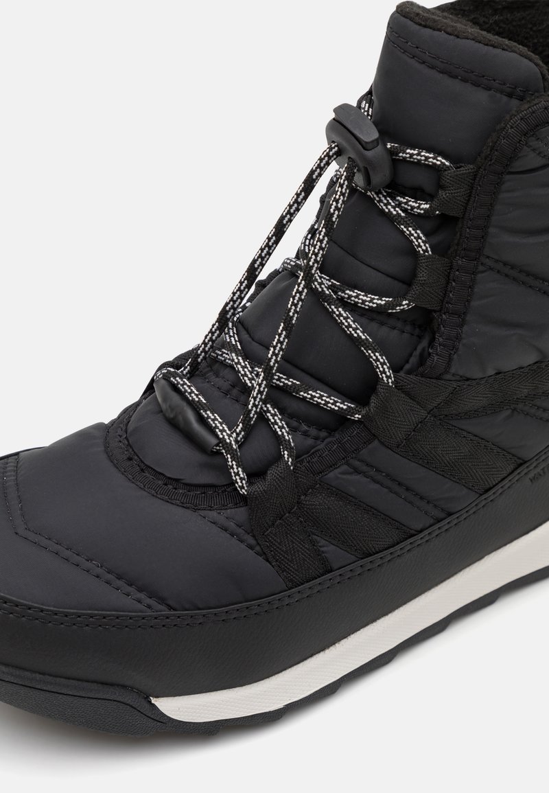 Schwarze isolierte Stiefel mit gepolstertem Obermaterial, strukturiertem Einsatz, Gummisohle und kontrastierender weißer Laufsohle sowie traditionellem Schnürsystem.