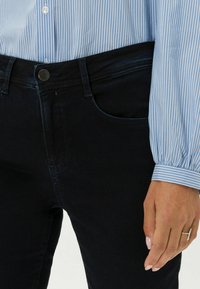 Dunkelblaue Denim-Jeans mit klassischem Schnitt, ausgestattet mit Fronttaschen, einem Metallknopfverschluss und Nähten entlang der Nähte.