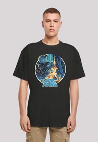 Black T-shirt featuring a colorful Star Wars graphic with characters and a helmet, round design, vibrant colors, and detailed artwork.