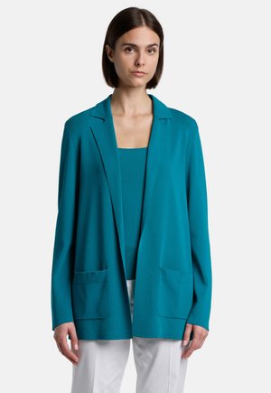 Blazer en teal en tissu léger avec un col à revers, devant ouvert, deux poches avant, superposé à un haut assorti. Texture lisse.
