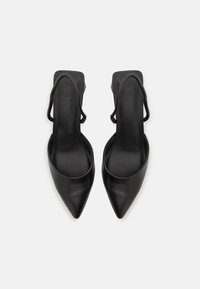 Black slingback heels with a pointed toe. Smooth leather material, minimalistic design, featuring a sleek ankle strap for secure fit.