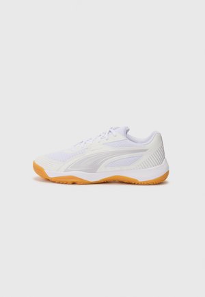 Bílé sportovní boty s horní částí z síťoviny, šedými akcenty a oranžovou gumovou podešví. Obsahují šněrování a texturovaný design pro lepší úchop.