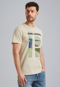 Beige bomulds t-shirt med grafisk design i grønne og blå nuancer, med teksten "PME LEGEND," rund halsudskæring og korte ærmer.