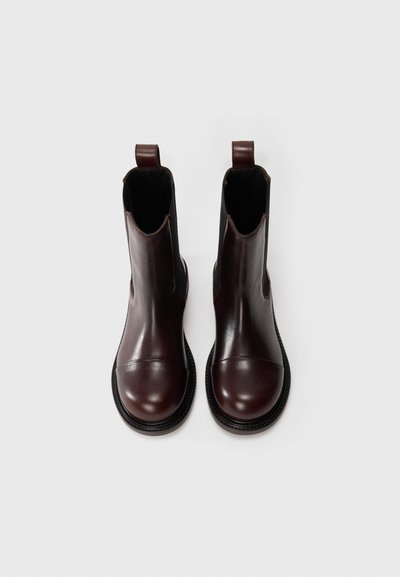 Ghete de gleznă din piele burgund cu vârf rotund, panouri laterale elastice și bucle pentru tragere, având o talpă texturată și un finisaj neted.