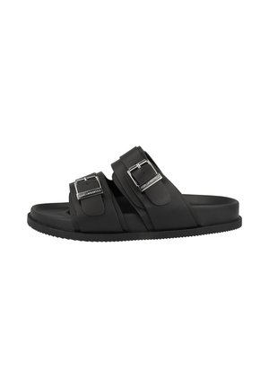 Sandalia negra tipo slide con dos correas ajustables con hebillas y suela plana, marca visible en el herraje de la hebilla sobre fondo blanco.