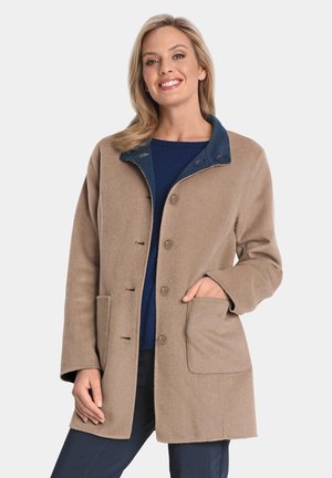 Beige wollen jas van een wolmix met een donkerblauwe kraag, voorknopen en zijzakken; zachte textuur en op maat gemaakte pasvorm met een gemiddelde lengte.