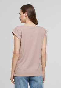 T-shirt en coton rose clair avec des manches courtes retroussées et un col rond, présentant une coupe décontractée et une texture douce.