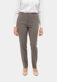 Tapered bruine broek van een gestructureerde stof, met een voorzak, riemlussen en een knoopsluiting, gecombineerd met een wit shirt.