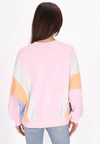 Felpa rosa con pannelli geometrici multicolore; presenta accenti grigio chiaro, arancione e blu. Tessuto morbido con un design a vestibilità morbida.