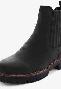 Bottine en cuir noir avec panneaux latéraux élastiques, surpiqûre marron et semelle crantée noire épaisse.