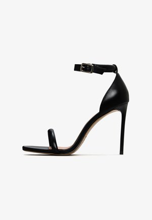 Czarna sandałka na wysokim obcasie z paskiem na kostce, charakteryzująca się gładkim wykończeniem ze skóry, otwartym noskiem i smukłym obcasem w kształcie szpilki.