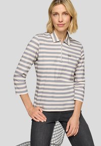 Striped polo shirt in light gray and cream, features a half zip, collar, and a small pocket with studded detailing. Smooth, stretchy fabric.